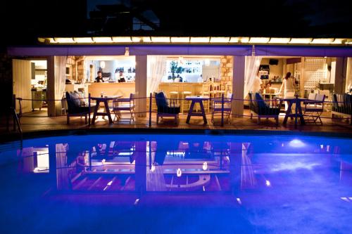 a swimming pool with tables and chairs and a restaurant at Oasis Beach Hotel in Skala