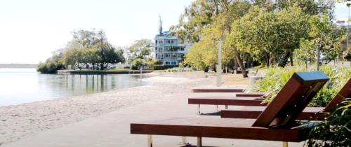 a row of benches sitting next to a body of water at Beachside One Bedroom Flat Retreat in Maroochydore