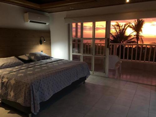 a bedroom with a bed and a balcony with a sunset at House of Sun and Water in Barranquilla