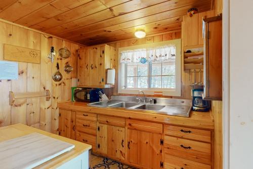 eine Küche mit Holzschränken, einem Waschbecken und einem Fenster in der Unterkunft Eagle's Nest in Greenville