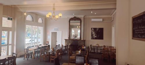 een eetkamer met tafels en stoelen en een spiegel bij Leura Hotel in Camperdown