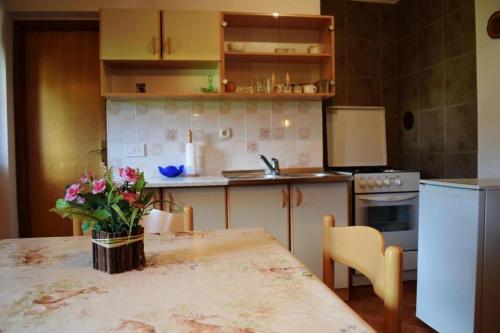 a kitchen with a table with a vase of flowers on it at Apartments with a parking space Mrkopalj, Gorski kotar - 20714 in Mrkopalj