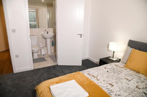 um quarto com uma cama e uma casa de banho com um lavatório em Crayford, Super Cosy 2-Bed Apartment em Dartford