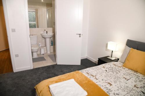 a bedroom with a bed and a bathroom with a sink at Crayford, Super Cosy 2-Bed Apartment in Dartford