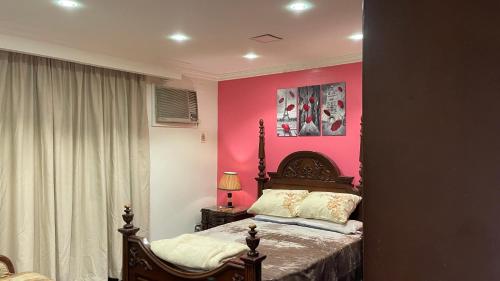 1 dormitorio con 1 cama con pared de color rosa en Fancy apartment close to airport fully furnished, en El Cairo