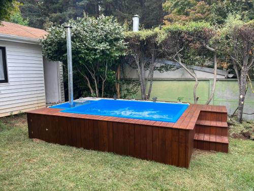 una piscina en un patio con terraza de madera en Acogedora casa en Pingueral, en Concepción