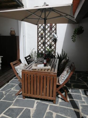 a table and chairs with an umbrella on a patio at Courtyard House - Sun, Barbecue, Beach in Sesimbra