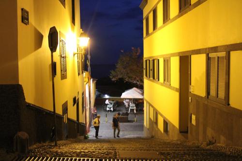 two people walking down a street at night at Alexia Room in Funchal