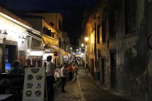 a group of people walking down a street at night at Alexia Room in Funchal