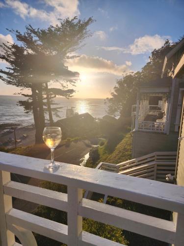 a glass of wine sitting on a white railing overlooking the ocean at Wharf Master's Inn in Point Arena