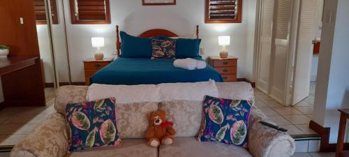 een slaapkamer met een bed en een bank met een teddybeer bij Eden House Retreat in Yungaburra