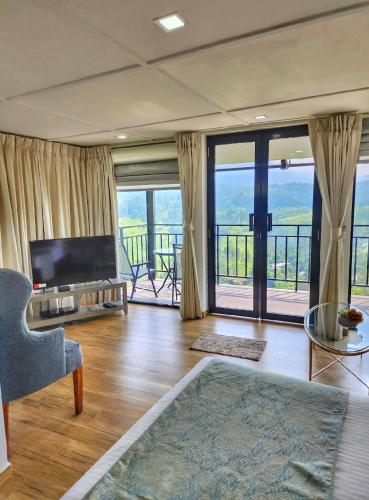 a living room with a couch and a television and sliding glass doors at Hummingbird St.Clare Villas in Dimbula