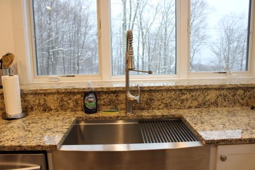 a kitchen sink with a faucet and two windows at Condo 7 Slopeside With Private Sauna and Hot Tub in Killington
