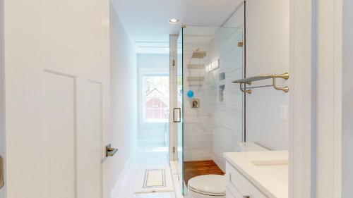 a white bathroom with a shower and a toilet at Modern 2BR 2BA with King bed-Fast Wi-Fi 75 inch OLED TV in Wilmington