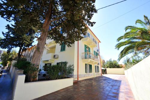 a building with a palm tree next to a street at Guesthouse Villa Vice in Split