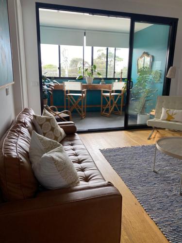 - un salon avec un canapé en cuir brun et une table dans l'établissement Beachside Apartment 108, à McCrae