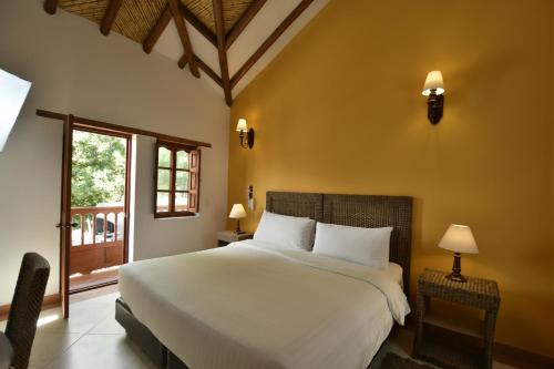 Un dormitorio con una gran cama blanca y una ventana en Hotel Campanario Real, en Villa de Leyva