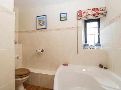 a bathroom with a tub and a toilet at Red Roof in Honiton