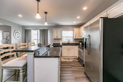 a kitchen with a stainless steel refrigerator and wooden floors at Cozy Modern Newbo Area Home in Cedar Rapids