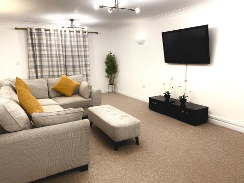 a living room with a couch and a flat screen tv at Angel view - 4 bed property- perfect for contractors & families in Milton Keynes