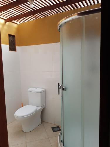 a bathroom with a toilet and a glass shower at Bidara Cottage in Labuhanpandan