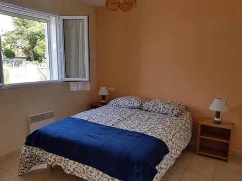une chambre avec un lit avec une couette bleue et une fenêtre dans l'établissement Charmante maison boisée près de la plage - 4 pers, animaux sur demande, jardin clos, calme assuré - FR-1-476-122, à La Faute-sur-Mer