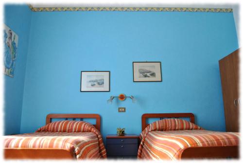 two beds in a room with a blue wall at Bed and Breakfast D'Angelo in Palermo