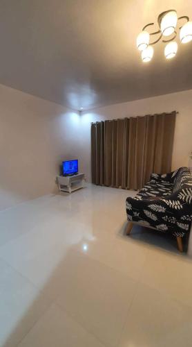 een woonkamer met een bed en een televisie bij Elvie Medida House for Rent in Boljoon