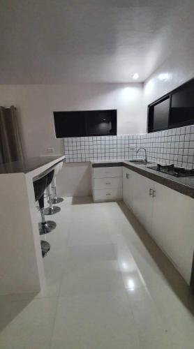 eine große weiße Küche mit Waschbecken und Arbeitsplatten in der Unterkunft Elvie Medida House for Rent in Boljoon