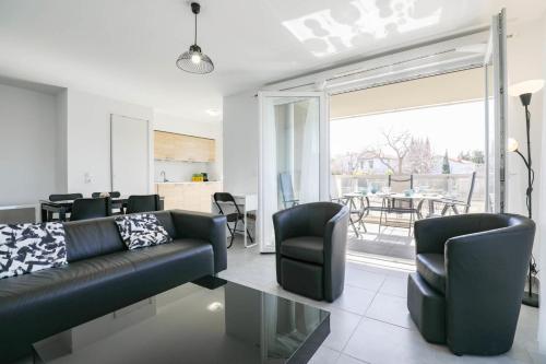 - un salon avec un canapé et des fauteuils en cuir noir dans l'établissement Le Michelet - Appart 2 ch avec terrasse et parking, à Marseille