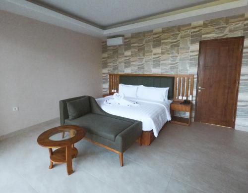 a bedroom with a bed and a chair and a table at Flamingo Bajo Waecicu in Labuan Bajo