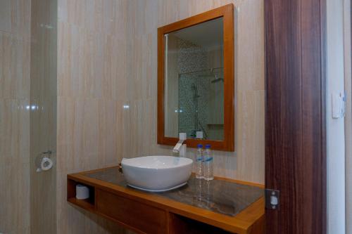 ein Bad mit einem Waschbecken und einem Spiegel in der Unterkunft Flamingo Bajo Waecicu in Labuan Bajo