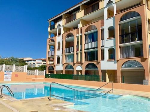 une piscine devant un immeuble dans l'établissement Studio cabine cosy avec piscine, proche Aqualand et plage, parking disponible, terrasse privative - FR-1-607-159, au Cap d'Agde