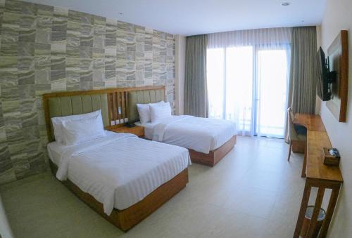 a hotel room with two beds and a stone wall at Flamingo Bajo Waecicu in Labuan Bajo