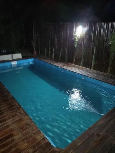 una piscina azul por la noche con luz en Duplex en Alquiler con Pileta Privada Pinamar Valeria del Mar en Valeria del Mar