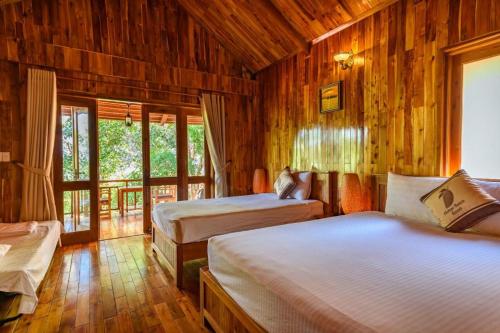 a bedroom with two beds in a room with wooden walls at Mango Beach Resort in Phú Quốc