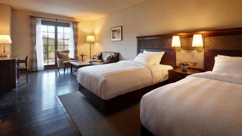 a hotel room with two beds and a chair at Lotte Arai Resort in Myoko