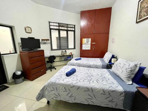 a bedroom with two beds and a desk and a tv at Barranco monumental in Lima