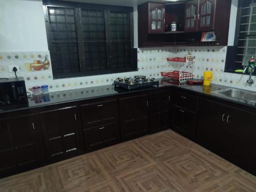 a kitchen with black cabinets and a wooden floor at Private Room! Alleppey Villa! in Alleppey