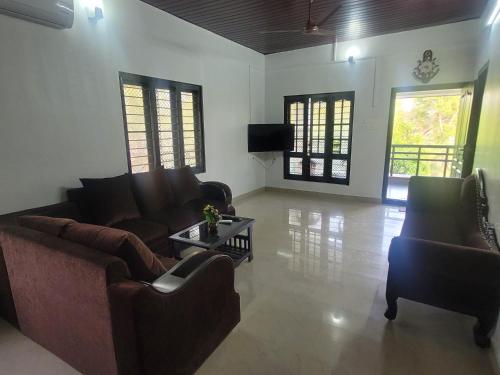 sala de estar con sofás, TV y mesa en Private Room! Alleppey Villa!, en Alleppey