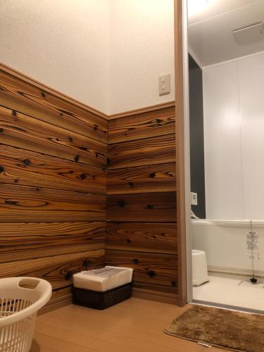 baño con paredes revestidas de madera y bañera en Minshuku Kawarabi-so en Nosegawa