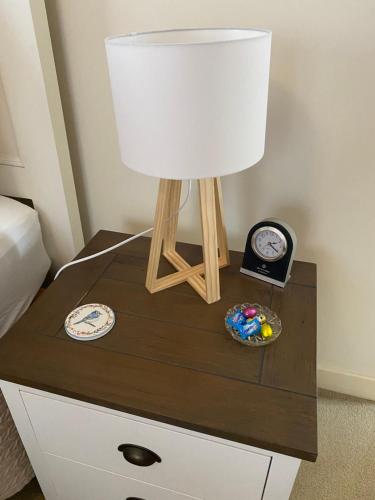 a nightstand with a lamp and a clock on it at Hideaway on Hume in Boonah