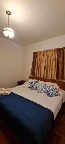 a bedroom with a large bed with blue and white pillows at Apartamento aconchegante em condomínio encantador. in Lambari