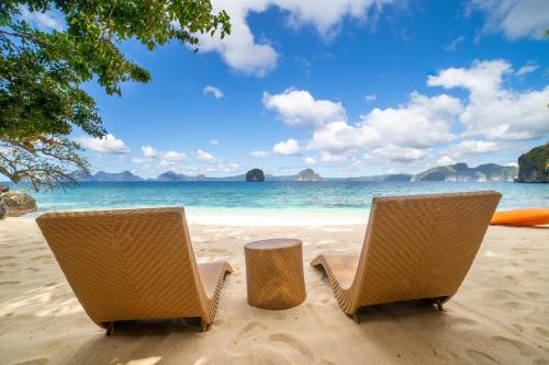 two chairs and a table on a beach at Kudugman Beach Cottages - El Nido in El Nido
