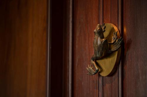 a frog door knocker on a wooden door at neil niwas in Bangkok