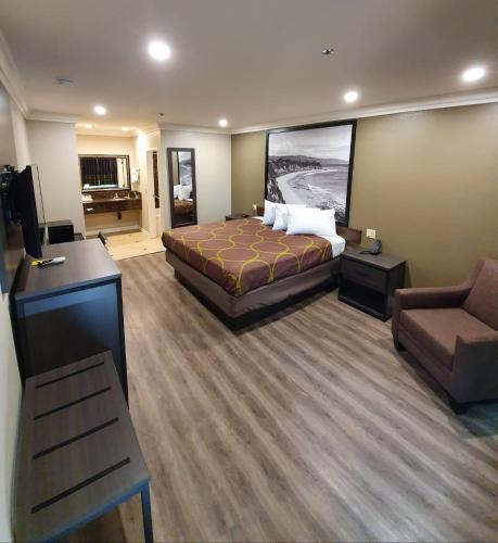 a hotel room with a bed and a tv and a couch at Super 8 by Wyndham Cypress Buena Park Area in Cypress