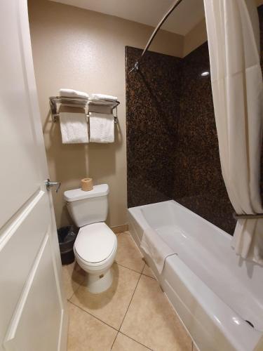 a bathroom with a toilet and a shower and a tub at Super 8 by Wyndham Cypress Buena Park Area in Cypress