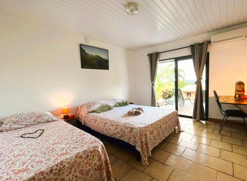 1 Schlafzimmer mit 2 Betten, einem Tisch und einem Fenster in der Unterkunft Pension Mave Mai in Nuku Hiva
