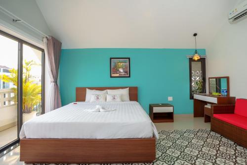 a bedroom with a large bed and a red chair at HAI DAO HOI AN VILLA in Hoi An