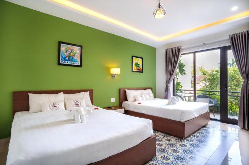 2 camas en una habitación con paredes verdes en HAI DAO HOI AN VILLA, en Hoi An